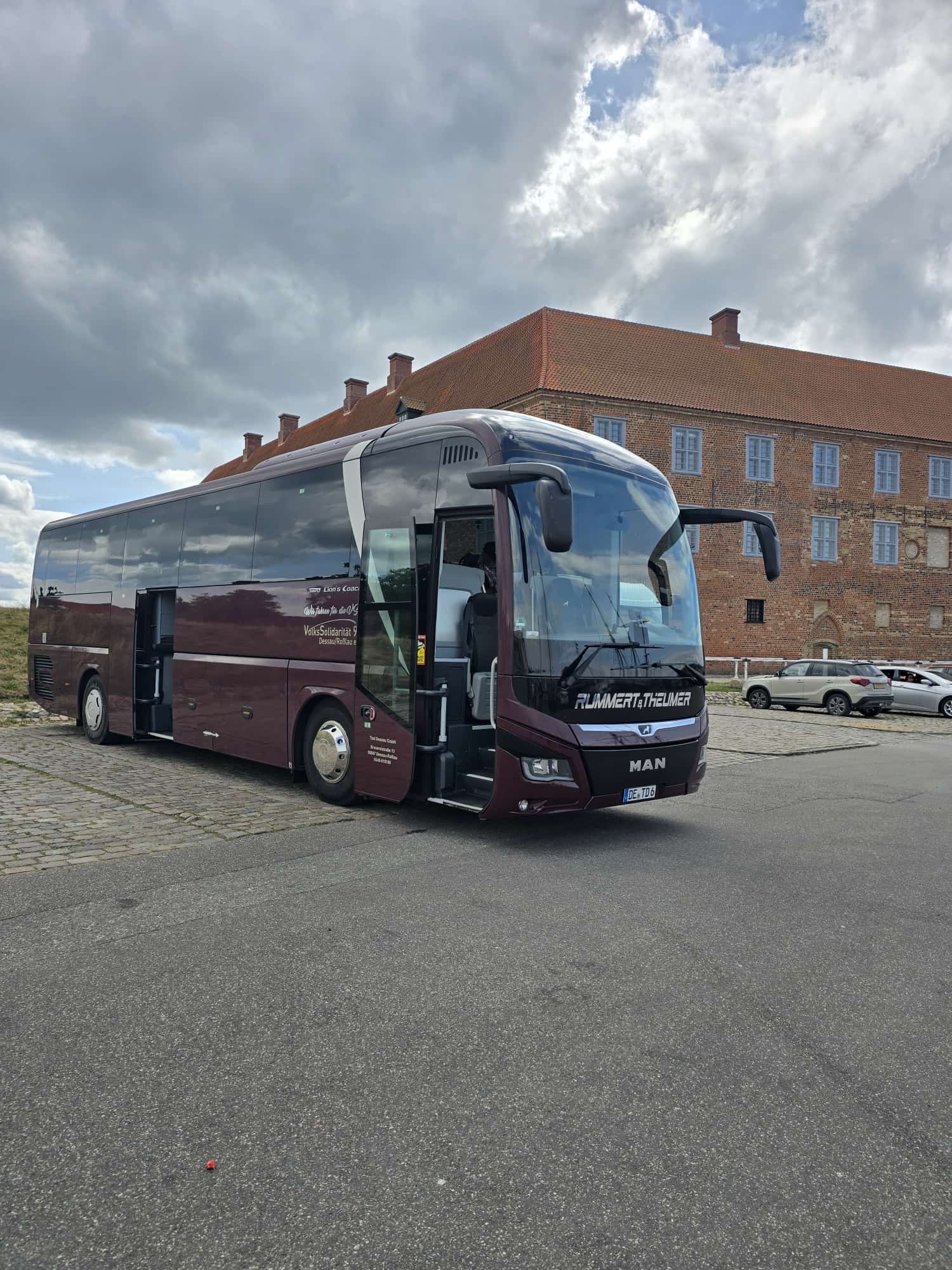 Reisebus mit 49 Sitzplätzen von Taxi Dessau GmbH vor historischer Backsteinfassade